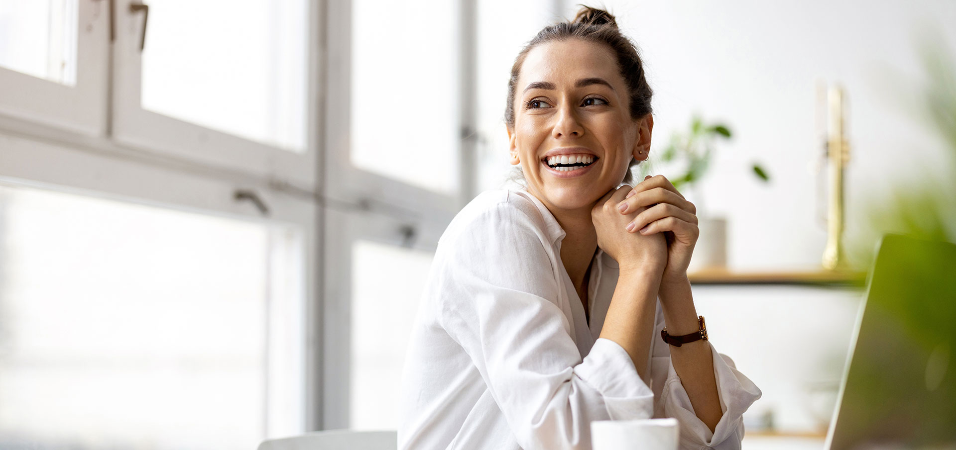 Bilde av en blid dame som sitter å jobber foran en datamaskin